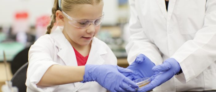 Girl in lab with Petri dishes doing hands-on experiment