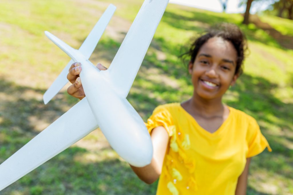 Happy teenager playing with model airplane outdoors