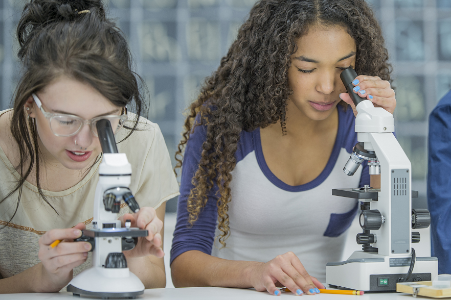 girls looking through microscope and learning about science with hands-on activities