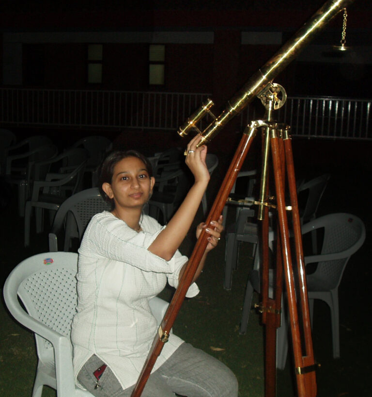 Young Parshati Patel looking through a telescope