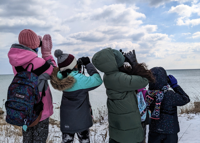 Girls using binoculars to look for birds in sky