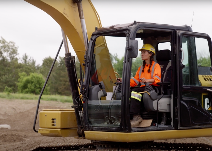 Woman in construction site driving digger