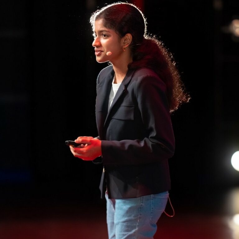 Bhavi standing on stage giving a talk