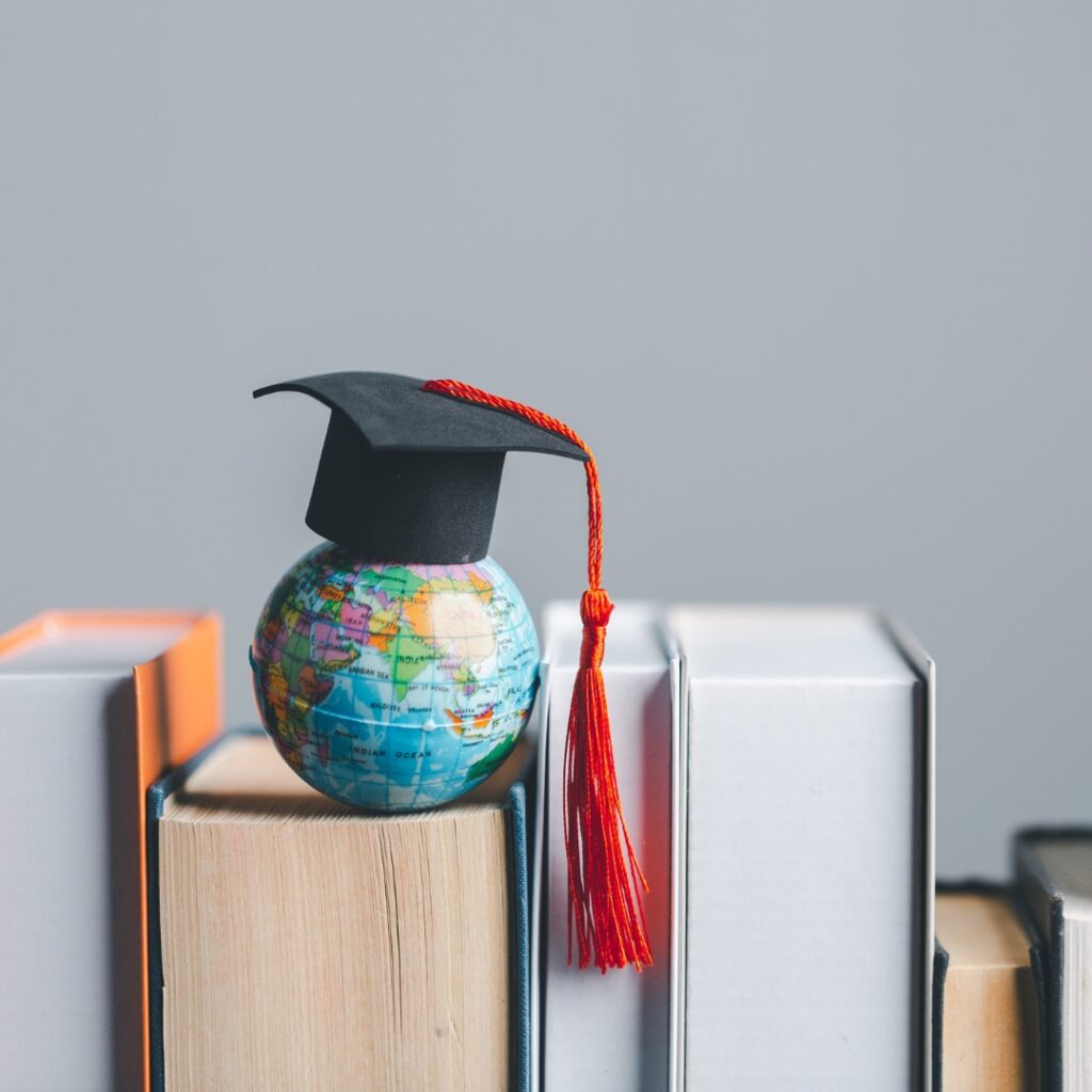 graduation hat on a globe ontop of books